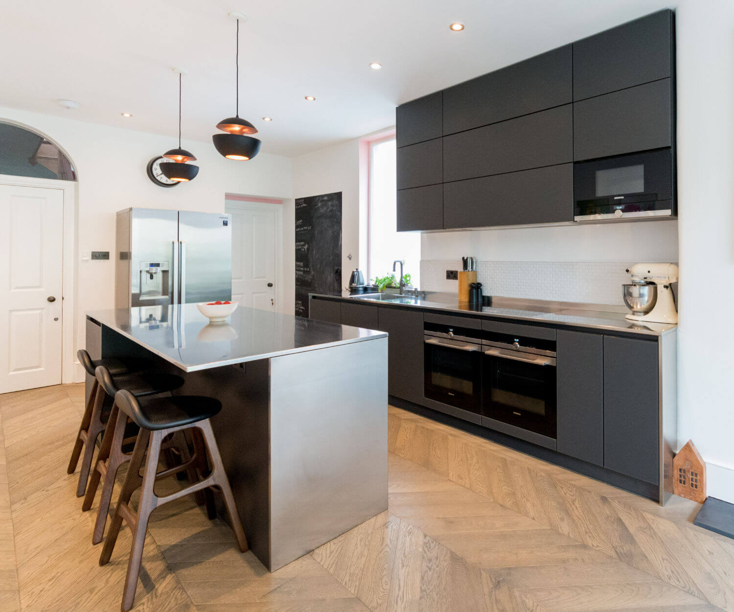 German kitchen with matt black glass door fronts and stainless steel worktop