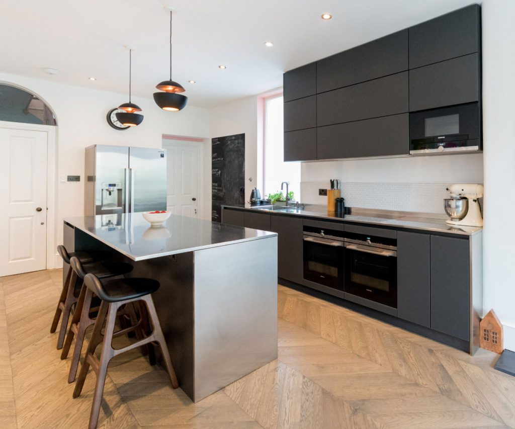 German kitchen with matt black glass handleless kitchen units and a stainless steel worktop