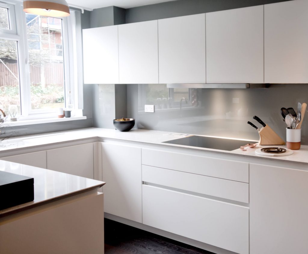 A white German kitchen with handleless kitchen units and a shark nose Silestone worktop