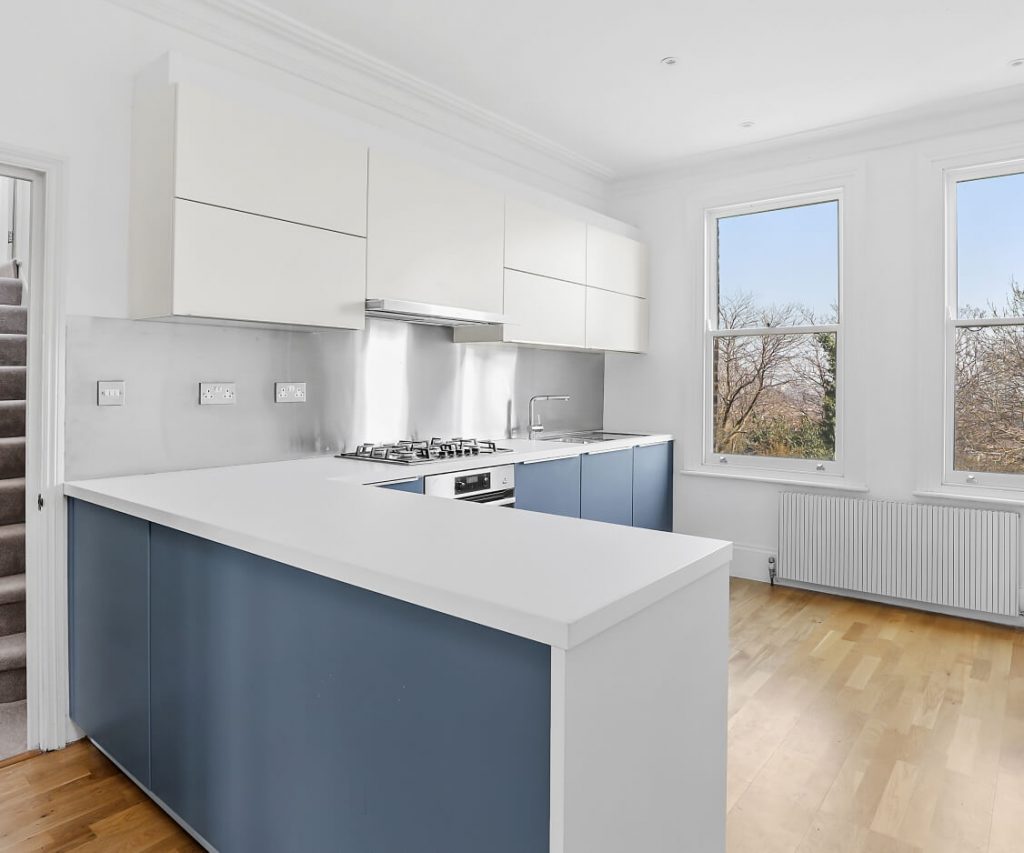 A German kitchen with blue kitchen units and a stainless steel splash back