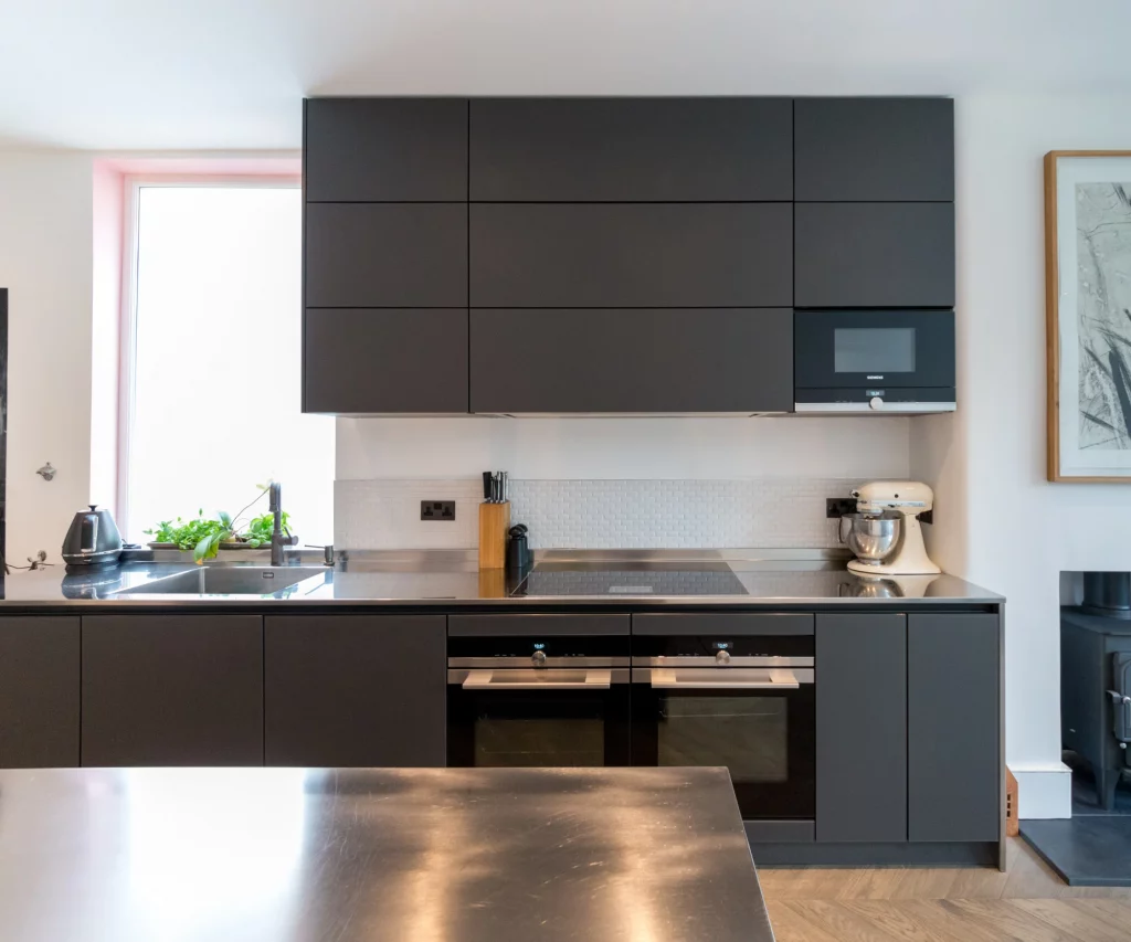 German kitchen with matt black glass doors and stainless steel worktop
